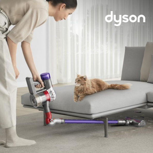 Woman using a Dyson cordless vacuum cleaner to clean underneath her sofa